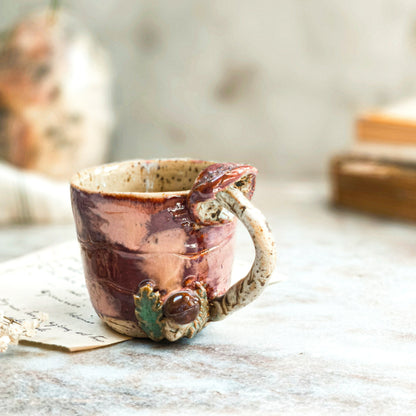 A handcrafted ceramic coffee cup in cinnamon red sitting on top of a table