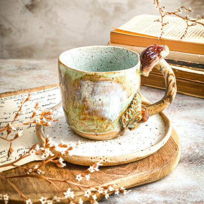 A cup with a mushroom handle on top of a handmade ceramic saucer plate in cappuccino white